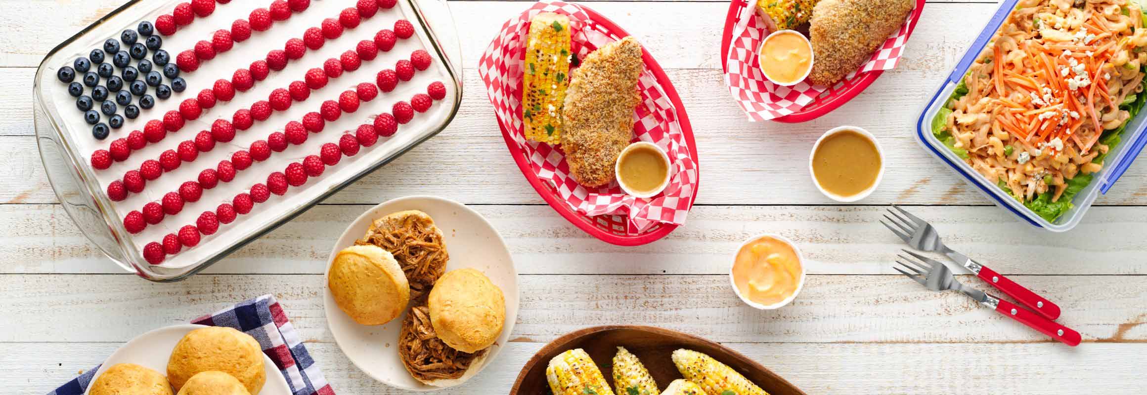 A festive table spread featuring a u.s. flag made of blueberries and raspberries, accompanied by dishes like cornbread, fried chicken, and salads.