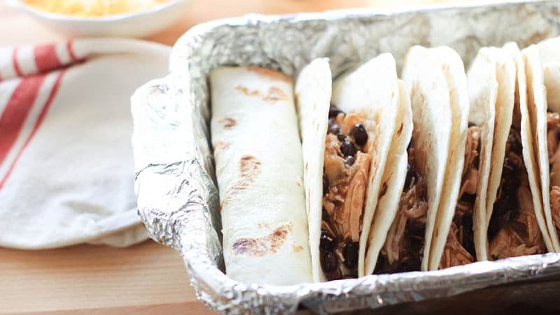 Divide the chicken mixture evenly among folded tortillas in a baking dish; wrap the tortillas around the filling and place seam-down into the pan.