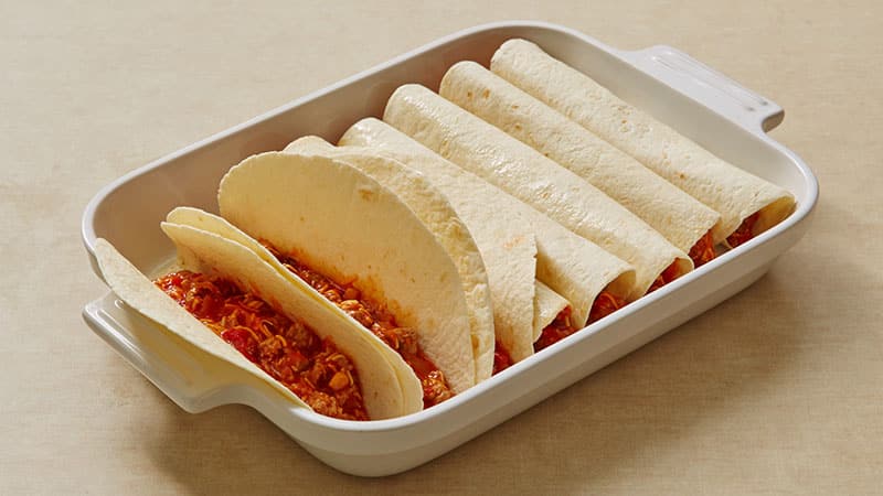 Divide the beef mixture evenly among folded tortillas in a baking dish; wrap the tortillas around the filling and place seam-down into the pan.